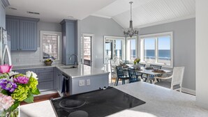 Cozinha moderna com uma ilha grande, área de jantar com vista e teto com padrão único.