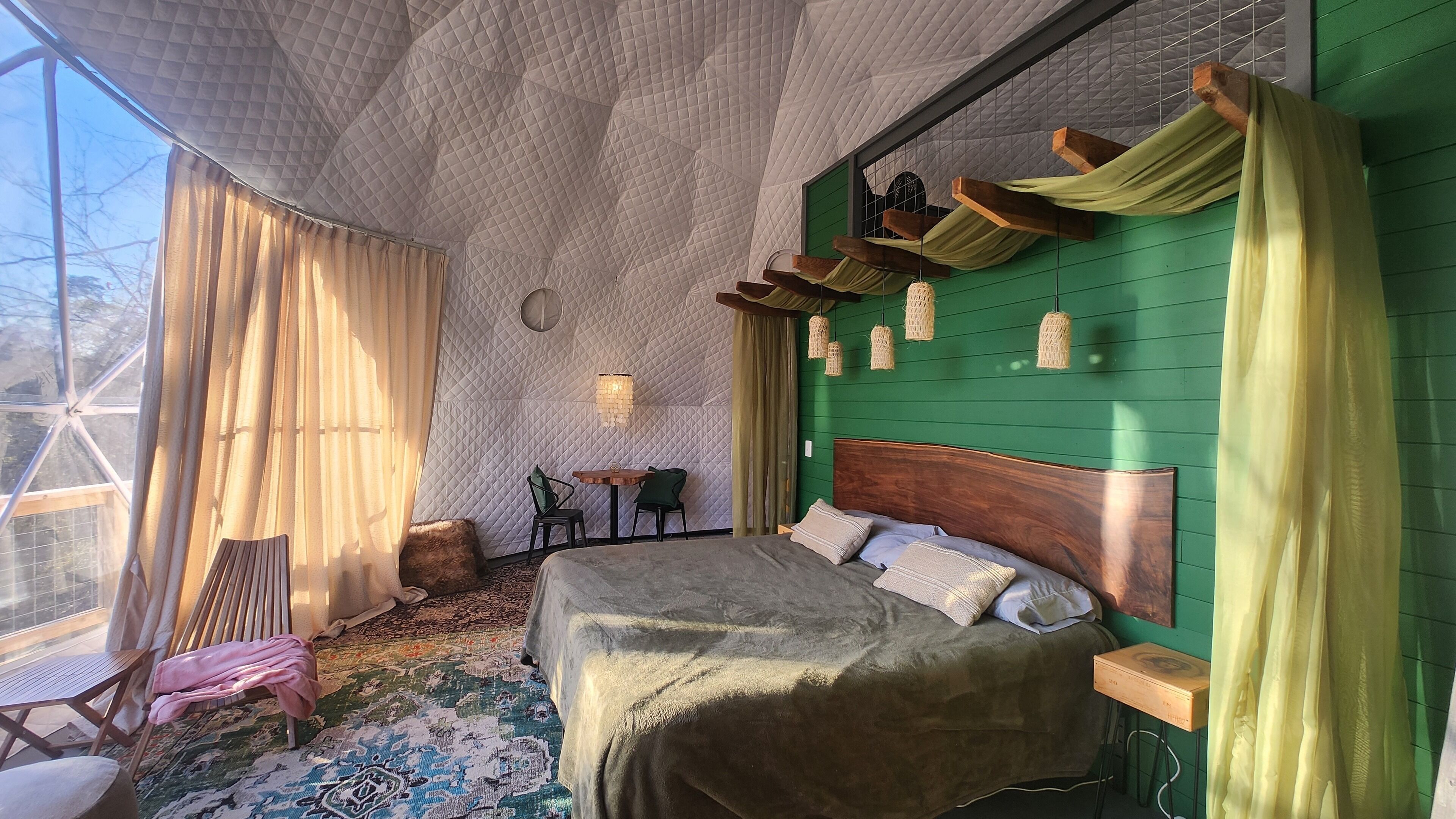 A cozy room with a large bed, a small table, and a chair.