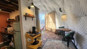 Ein gemütliches Zimmer mit einem Holztisch und -stühlen, einer kleinen Ablage für Küchenutensilien und einem gemusterten Teppich.