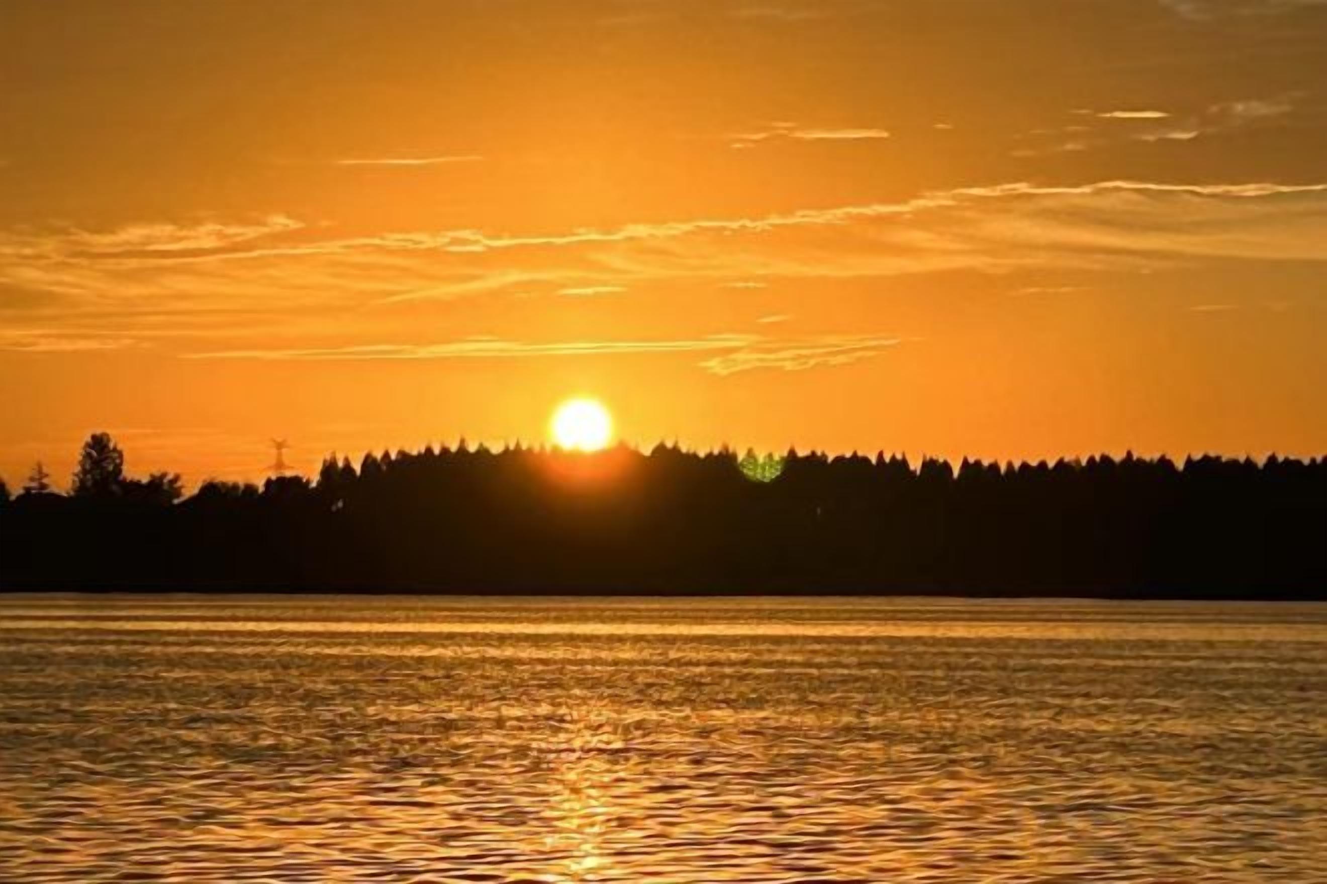 A sunset over a body of water with a forested shoreline.