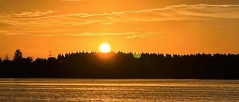 A sunset over a body of water with a forested shoreline.