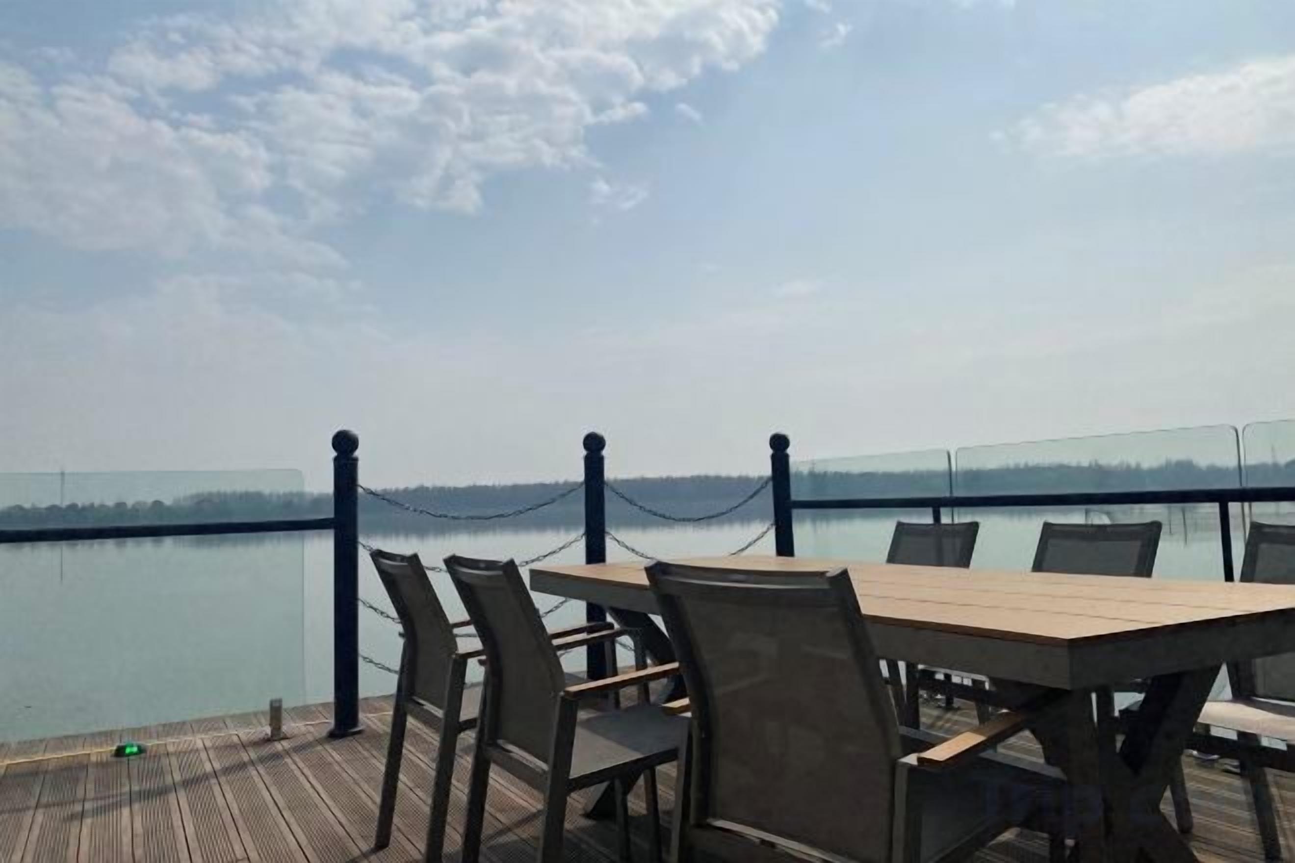 An outdoor dining area with a view of a calm body of water and a clear sky.