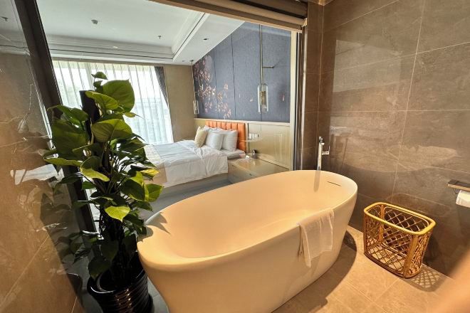 Een moderne badkamer met een vrijstaand bad, een grote potplant en een rieten mand.