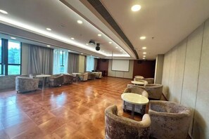 Um quarto espaçoso com uma mesa comprida e cadeiras, uma tela de projetor e um janelão.