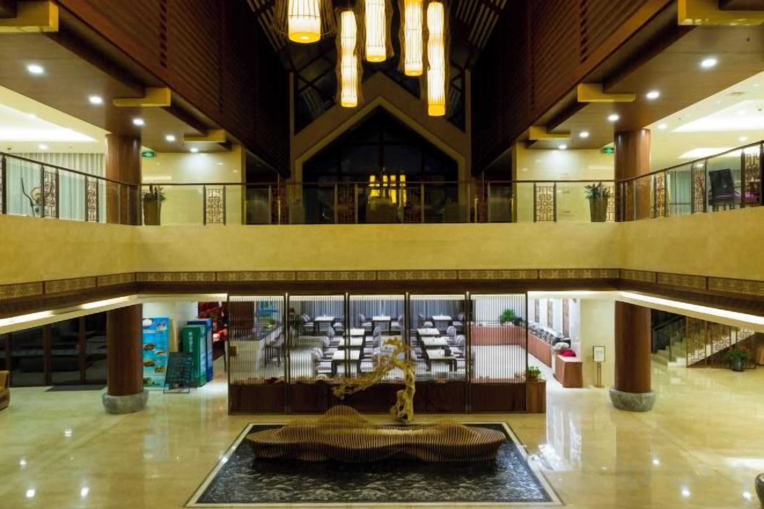 A spacious lobby with a central fountain, multiple levels, and a dining area in the background.