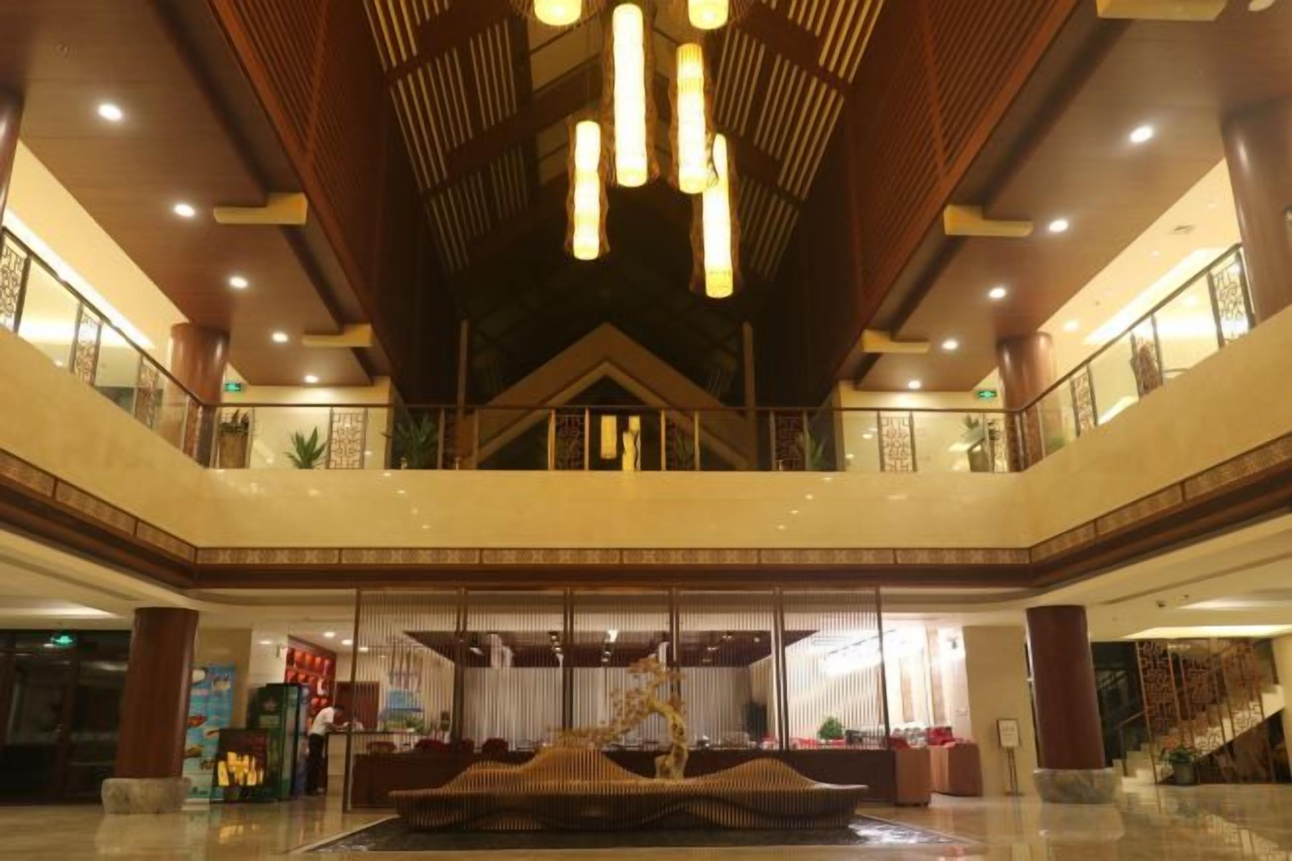 A spacious lobby with a high ceiling, a central seating area, and a staircase leading to an upper level.