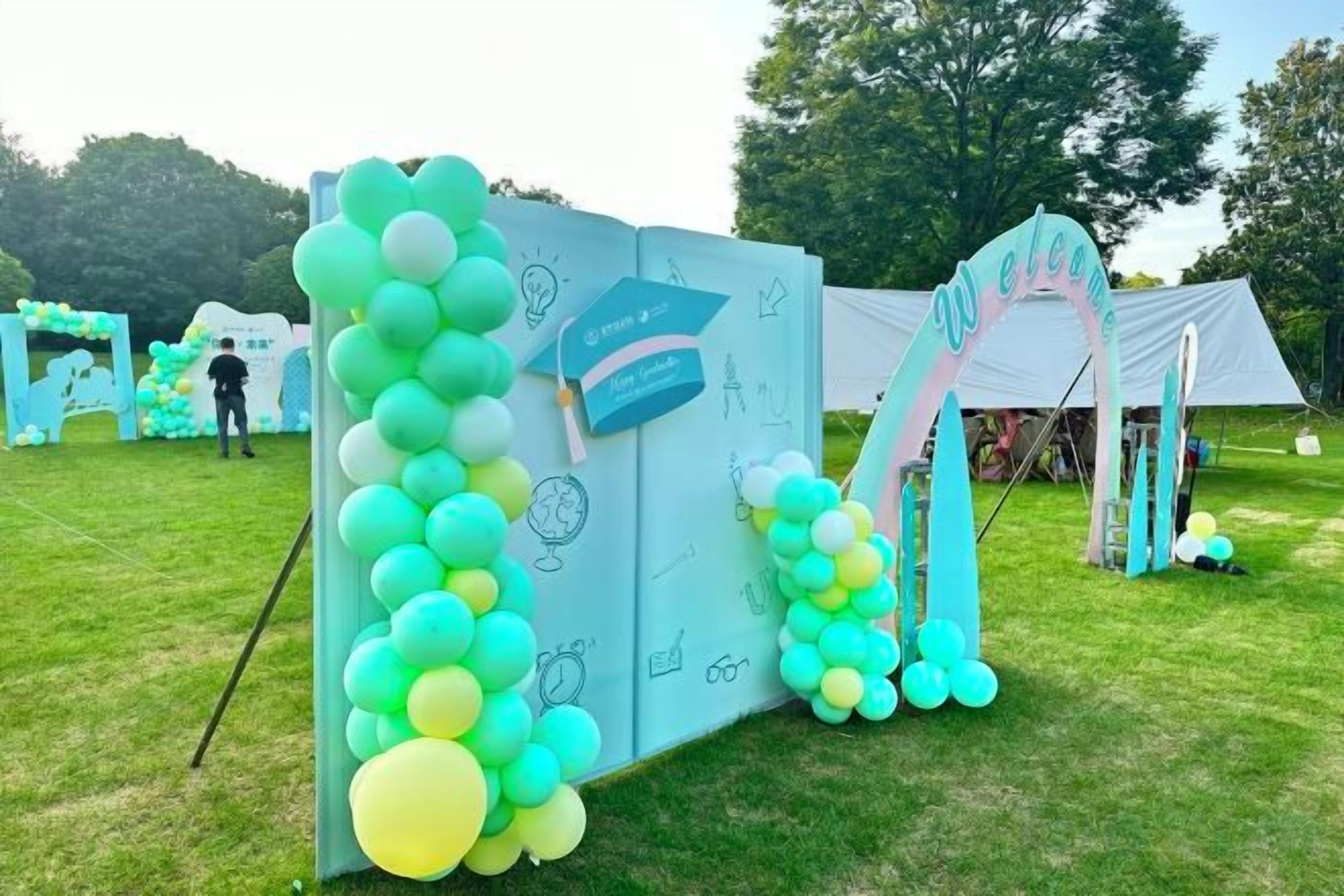 Un espacio para eventos con carpas, un arco de globos y un letrero.