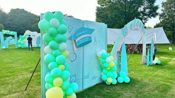 Un espacio para eventos con carpas, un arco de globos y un letrero.