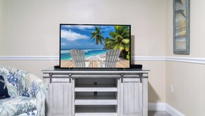 A flat-screen TV on a wooden entertainment center with a beach scene on the screen.