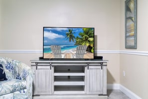 A flat-screen TV on a wooden entertainment center with a beach scene on the screen. - Duck Key Waterfront Villa w/ 2 Free Kayaks & near 2 Public Marinas (Marathon)