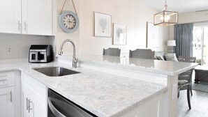 A modern kitchen with white cabinetry, a large island, and a built-in dishwasher.