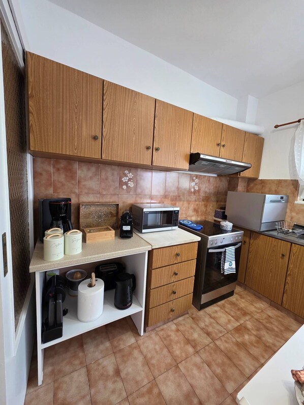 Una cocina con armarios de madera, microondas, cafetera y estufa.