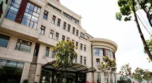 A multi-story building with a curved facade, large windows, and a covered entrance area. - GreenTree Alliance Hotel (Shanghai Baoshan District Meilan Lake Yueluo Road) (Shanghai)