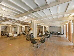 A spacious indoor area with multiple tables and chairs, wooden flooring, and a high ceiling with exposed beams. - GreenTree Alliance Hotel (Shanghai Baoshan District Meilan Lake Yueluo Road) (Shanghai)