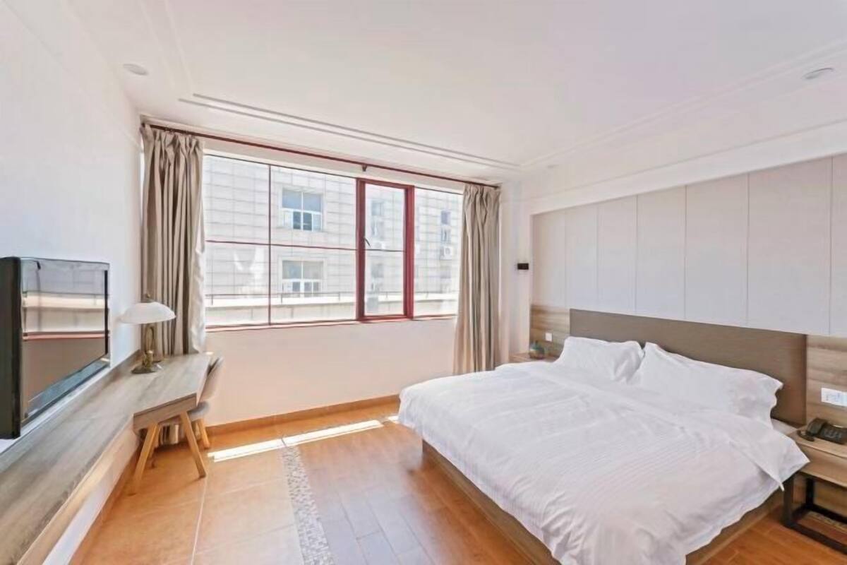 Ein Hotelzimmer mit Bett, Schreibtisch, Fernseher und einem Fenster mit Vorhängen.