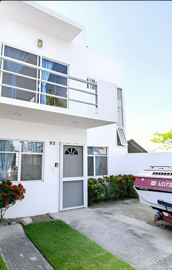 A modern two-story building with a white exterior, a visible number '52' on the door, and a boat parked outside.