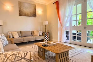 A living room with a sofa, a coffee table, a lamp, and a door with windows.