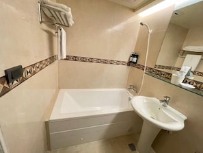 A bathroom with a bathtub, a sink, and a shower. - New City Hotel (Taipei)