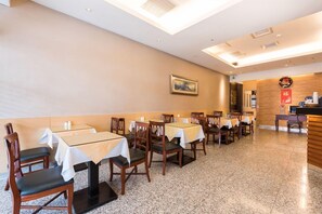 A restaurant with multiple tables and chairs, a wooden reception desk, and a ceiling with skylights. - New City Hotel (Taipei)