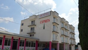 Ein mehrstöckiges Hotel namens "HOTEL CIPRÉS" mit Balkonen und einem Parkplatz.