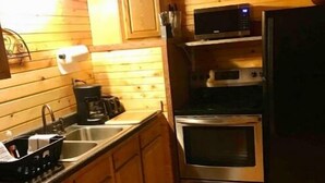 Une cuisine compacte dotée de meubles en bois, d’un évier en acier inoxydable, d’une machine à café, d’un four à micro-ondes et d’un four traditionnel.