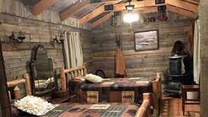 Une chambre confortable dans un chalet en rondins, avec deux lits en bois, une cheminée et un décor rustique.