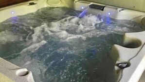Un bain à remous avec une structure extérieure en pierre et un intérieur en bois.