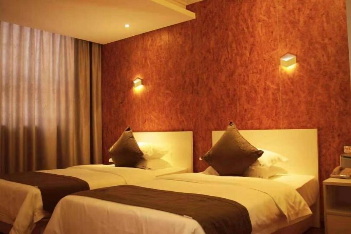 A hotel room with two beds, a wooden textured wall, and two wall-mounted lights.