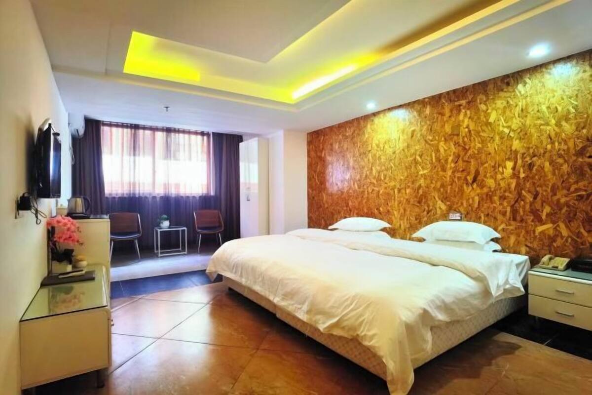 A hotel room with a bed, bedside table, and a desk with a chair.
