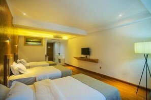 Una habitación de hotel con dos camas, un televisor en la pared y una lámpara.