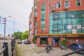 A multi-story building with a commercial ground floor, featuring a large glass storefront and a signboard. - Hengji Hotel (Shanghai Hongkou Football Stadium Dongbaoxing Road Subway Station) (Shanghai)