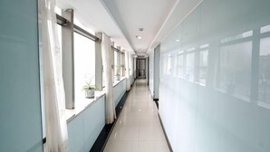 A long, narrow hallway with large windows on one side and a plain wall on the other. - Hengji Hotel (Shanghai Hongkou Football Stadium Dongbaoxing Road Subway Station) (Shanghai)