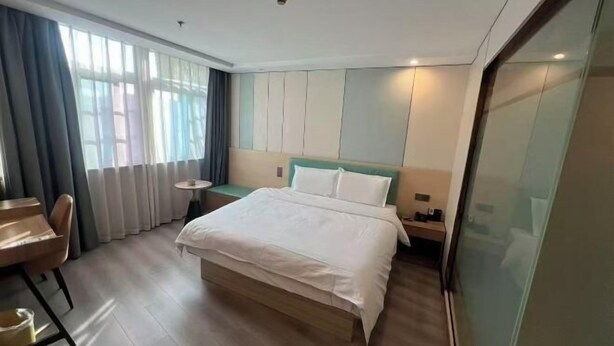 A hotel room with a bed, a desk, a chair, and a window with curtains. - Hengji Hotel (Shanghai Hongkou Football Stadium Dongbaoxing Road Subway Station) (Shanghai)
