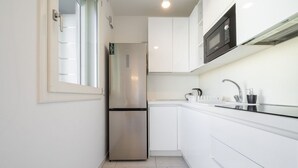 A modern kitchen with white cabinets, a stainless steel refrigerator, a microwave, and a sink with a faucet. - Ada Bright Escape Apartment (Cagliari)