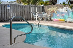 A swimming pool with a metal ladder, a wooden fence, and a mural with flamingos and palm trees. - Tidepool Manor - Newly Remodeled -Walk to Beach -Private Heated Pool - Sleeps 15 (Panama City)