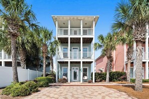 A two-story building with a balcony on the ground floor and a covered porch. - Tidepool Manor - Newly Remodeled -Walk to Beach -Private Heated Pool - Sleeps 15 (Panama City)