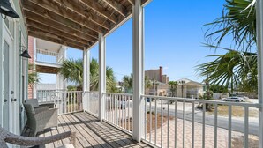 Una terraza de madera con mobiliario exterior y vistas a la calle y edificios.