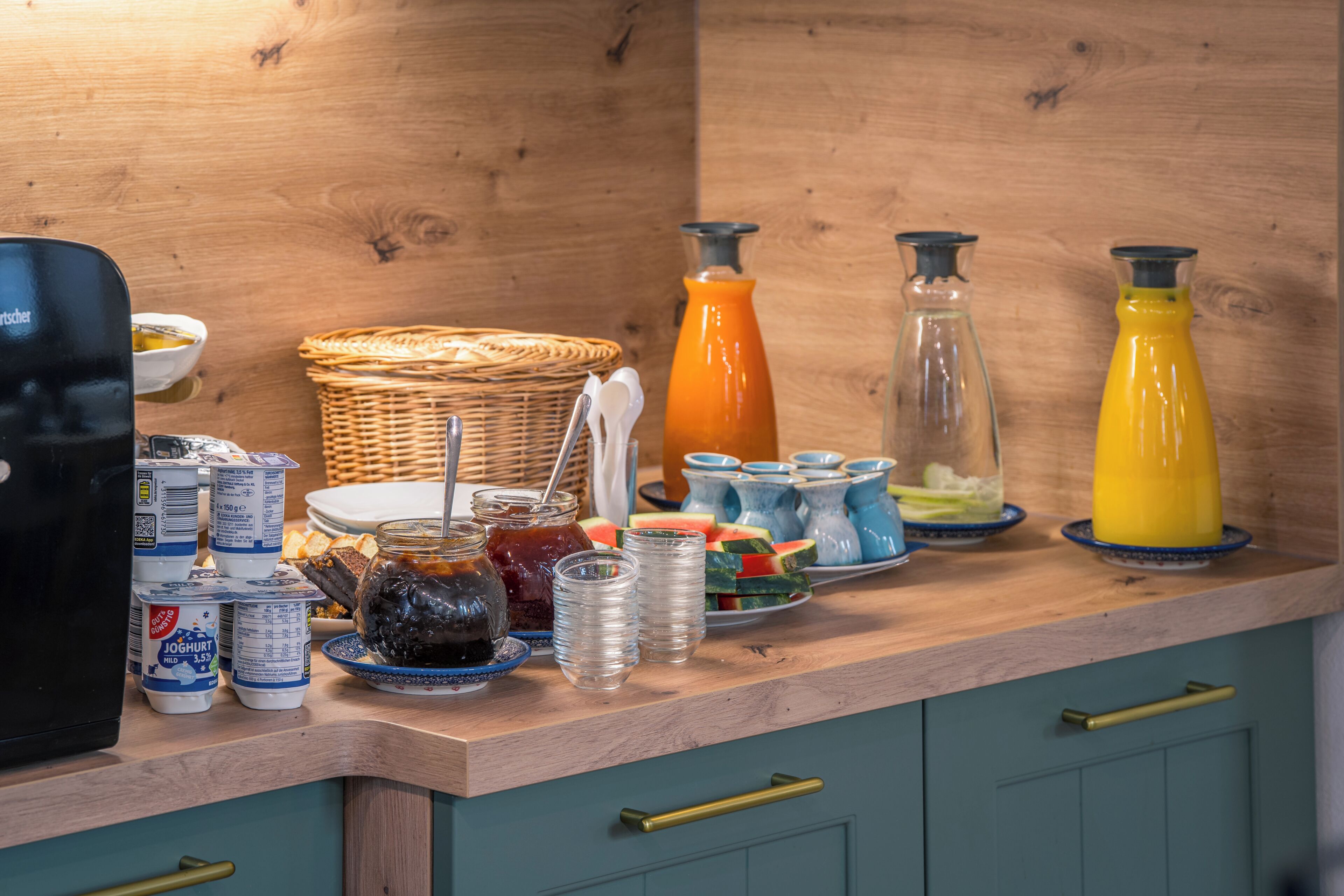 Een keukentafel met diverse etenswaren en containers, waaronder potten, borden en een mand.