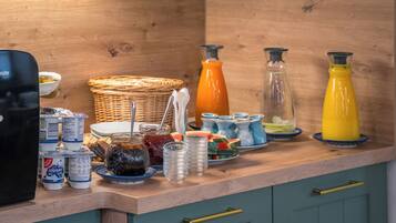 Een keukentafel met diverse etenswaren en containers, waaronder potten, borden en een mand.