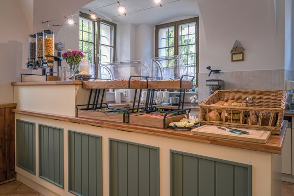 A buffet setup with various food stations, a coffee machine, and a wicker basket with bread. - Hotel Zum Hothertor (Görlitz)