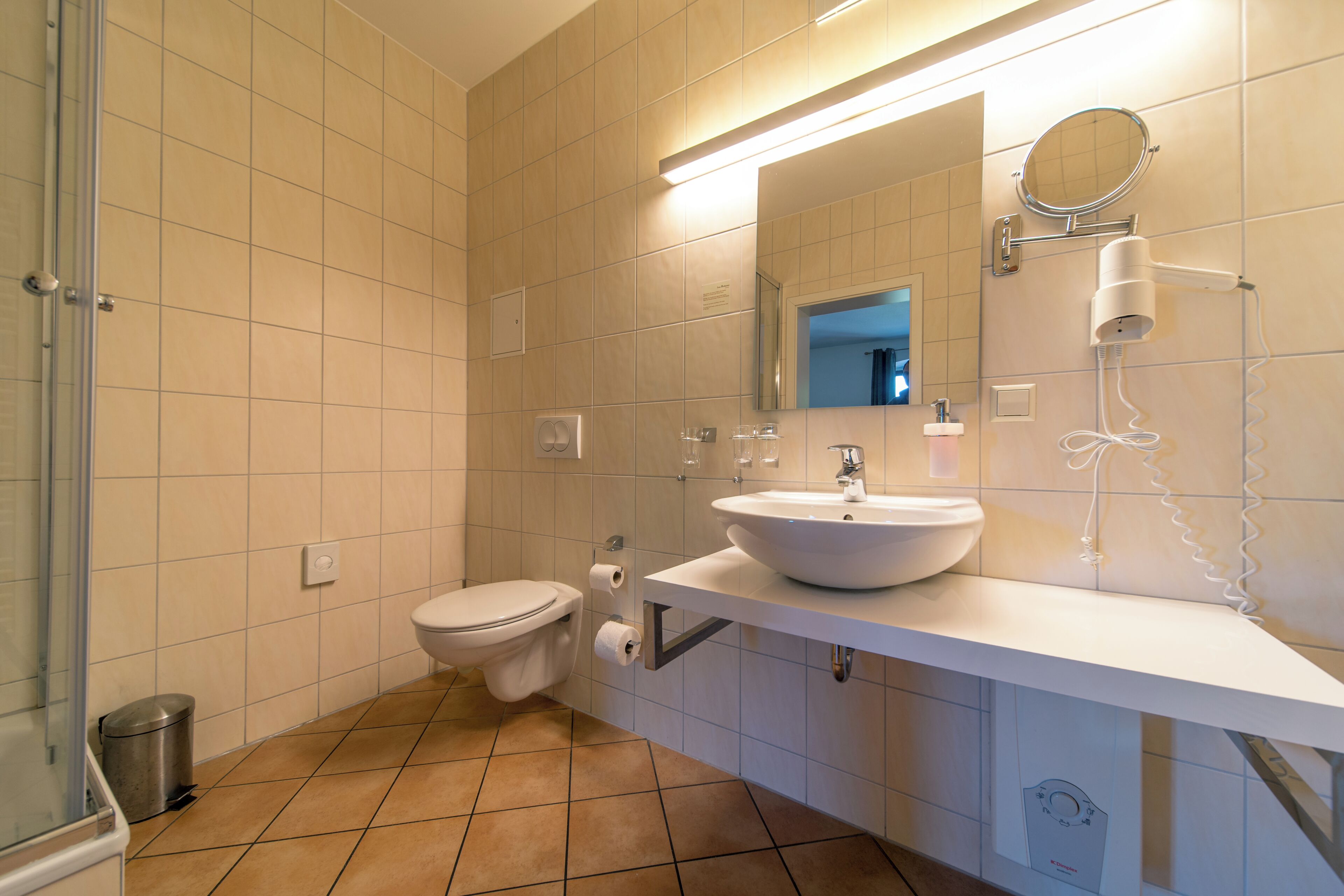 Un baño con inodoro, lavabo, espejo y secador de pelo.