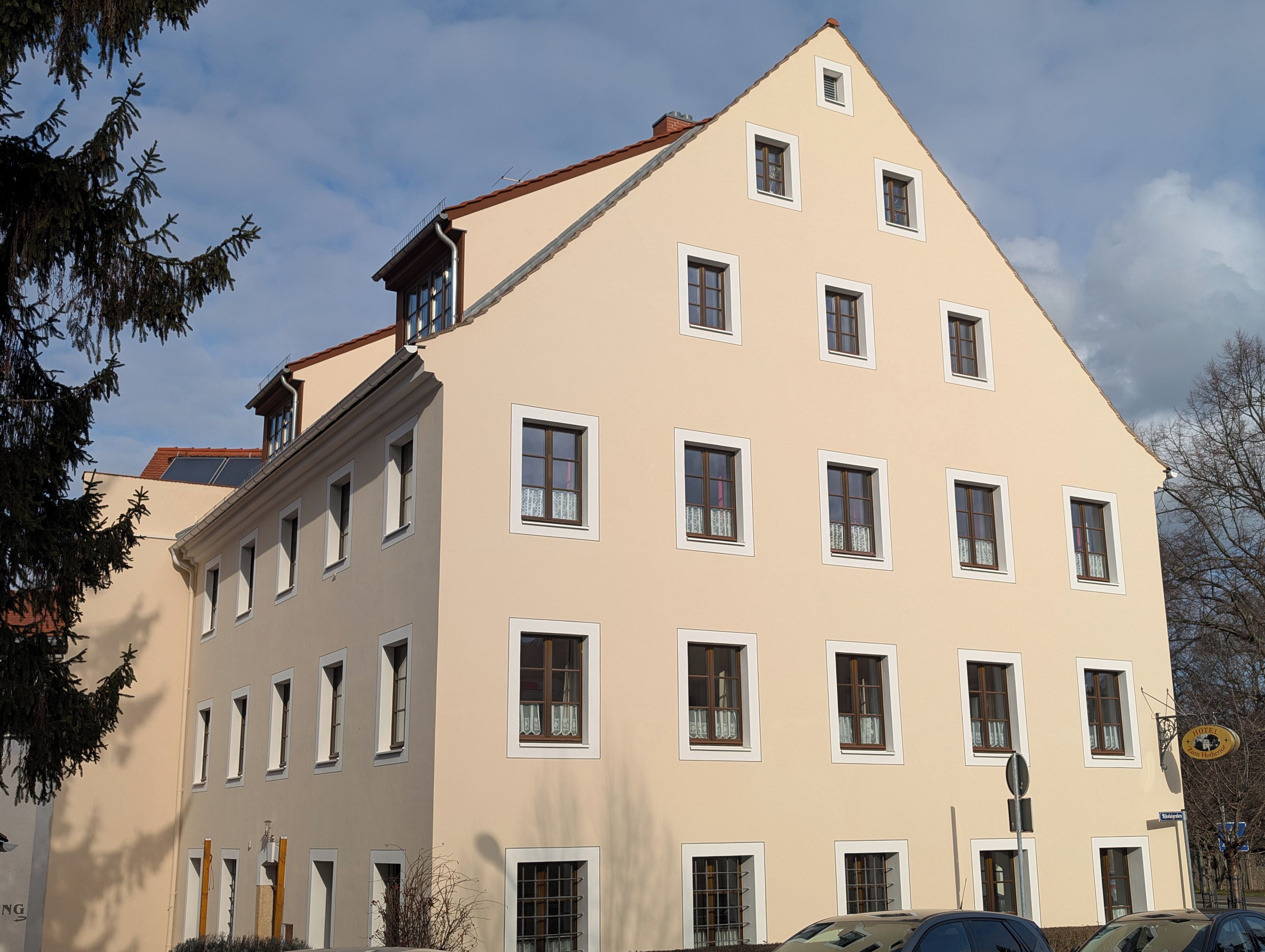 Ein mehrgeschossiges Hotel mit symmetrischer Fassade, zahlreichen Fenstern und einem sichtbaren Schild, das es als Hotel kennzeichnet.