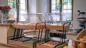 A buffet with various food items, a coffee machine, and a window with a view of greenery. - Hotel Zum Hothertor (Görlitz)