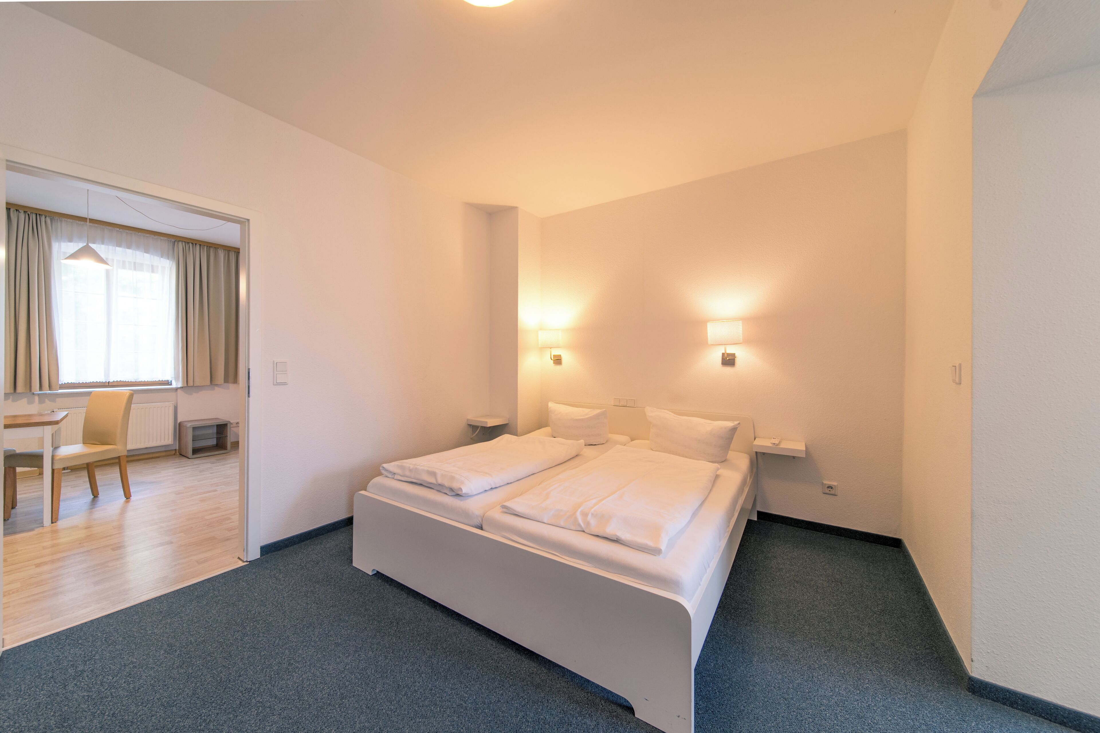 Ein Hotelzimmer mit einem Bett, Nachttischlampen, einem Schreibtisch und einem Sessel.