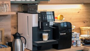 A coffee machine, a milk frother, and a coffee pot on a wooden counter. - Hotel Zum Hothertor (Görlitz)