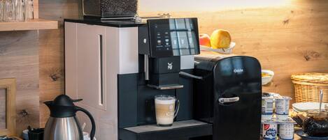 A coffee machine, a milk frother, and a coffee pot on a wooden counter.