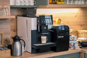 En kaffemaskin, en mjölkskummaskin och en kaffekanna står på en träbänk.