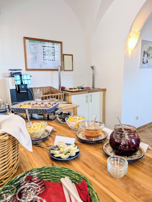 A dining area with a wooden table set for a meal, a coffee machine, and a framed menu on the wall. - Hotel Zum Hothertor (Görlitz)