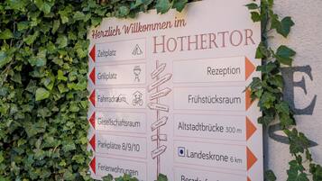 Señal direccional con flechas que indican diferentes servicios del hotel, como recepción, restaurante y estacionamiento.
