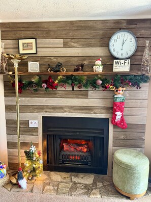 A fireplace with a clock and a Wi-Fi sign above it, surrounded by Christmas decorations. - Smokies Romantic Retreat, 1BR/1BA, Private Hot Tub, 15min Walk to DT Gatlinburg (Gatlinburg)